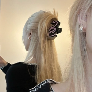 Dettaglio di una grande pinza per capelli in acetato nero e rosa su modella
