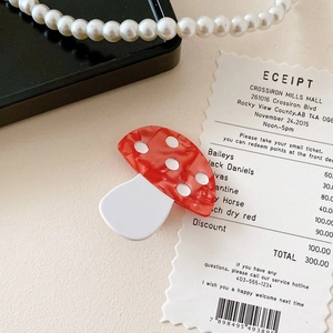 Close-up of a mushroom hair clip with red and white polka dots on a black jewelry box