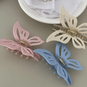 Detailansicht der hohlen Schmetterlings-Haarklammern in Pastellrosa, Beige und Blau