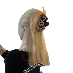 Grande molletta per capelli in acetato nero con scritta rosa su capelli lunghi biondi