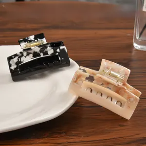 Detail of square acetate hair claws in marble black-white and soft beige-orange patterns