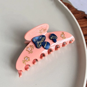 Détail de la pince à cheveux en acétate rose avec décor champignons et fleurs dorées