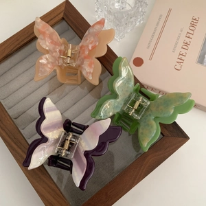 Three elegant acetate butterfly hair claws in peach, green, and purple with marble texture