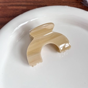 Détail de la pince à cheveux en acétate à motif marbre beige sur assiette céramique