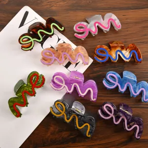 Detail showing wavy acetate hair claws in various marble colors and patterns on a desk