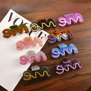 Close-up of 9-piece large acetate claw clips set with wavy lines on a wooden desk