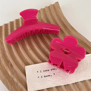 Two-piece vibrant magenta hair claw set with flower and arc shapes on wood tray