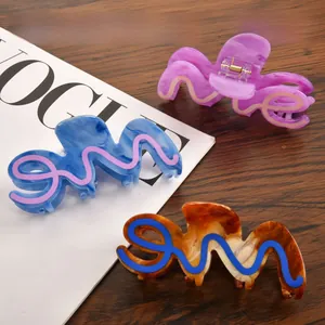 Macro detail of wave-shaped acetate hair claws in lavender, blue, and amber colors