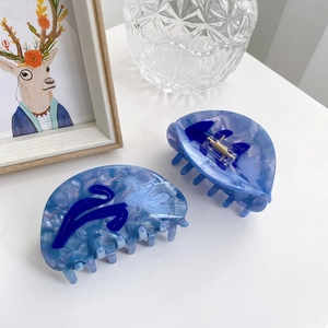 Pince à cheveux fleurie en acétate bleu marbré avec ressort en métal sur bureau