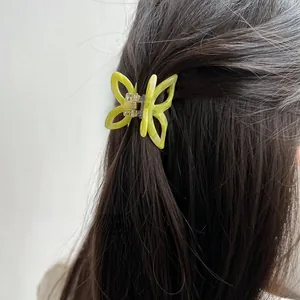 Detail view of yellow-green marbled acetate butterfly hair claw clip on dark hair