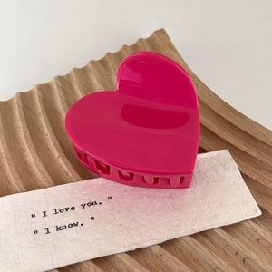 Detail view of rose pink heart-shaped acetate hair claw clip on wooden tray decoration