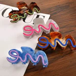 Close-up of four large acetate shark hair claws in tortoiseshell and marble patterns