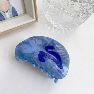 Détail d'une pince à cheveux en acétate bleu marbré avec motif floral, vue à 45 degrés