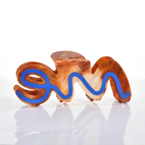 Close-up of brown tortoiseshell acetate hair claw with artistic blue wave letter design