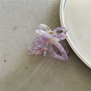 Close-up of a purple marble acetate butterfly hair claw clip with golden metal spring
