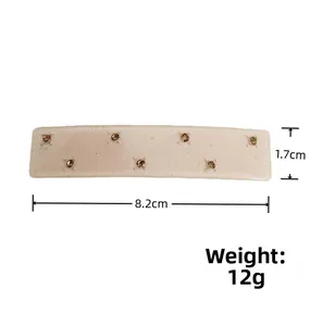 Détail d'une barrette blanche avec strass ambrés et dimensions de taille 8,2 cm