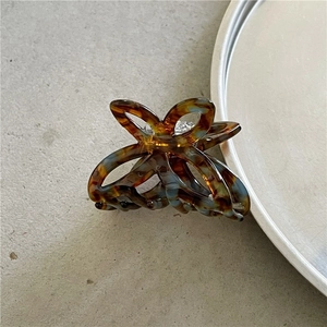Detail of a butterfly-shaped amber acetate hair claw clip with vintage hollow design