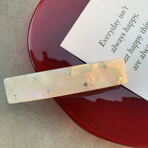 Détail d'une barrette en acétate marbré avec strass brillants et reflets arc-en-ciel