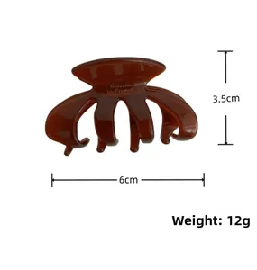 Detail showing amber acetic acid hair claw clip dimensions 6cm by 3.5cm on white backdrop