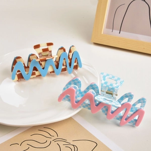 Detail of checkered hair claws with wavy edges in blue and pink acetate finish