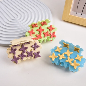 Detailed close-up of three cloud-shaped acetate hair claws with colorful floral patterns