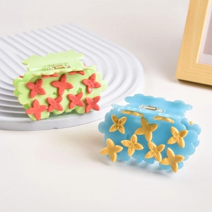 Detail of floral acetate hair claws in green and blue colors on a wavy tray