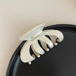 Detail view of cream acetate hair claw clip with golden Barette la France text branding