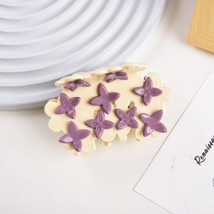 Detail of a creamy white acetate hair claw clip featuring purple 3D floral embellishments