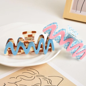 Checkerboard hair claw clips with wavy edges in macaron colors on a white ceramic plate