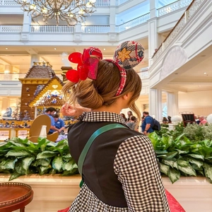 Rear view of a person wearing a Disney Minnie ear headband with red bow and plaid pattern