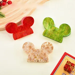 Detailed close-up of acetate Mickey-shaped hair claws in festive red, green and cream marble