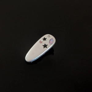 Close-up of silver metal star hair claw clip with colorful rhinestones on black background
