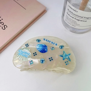Close-up of shell-patterned acetate hair claw with blue starfish and crystal accents