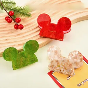 Close-up of Mickey-shaped acetate hair claws in red, green, and beige marble patterns