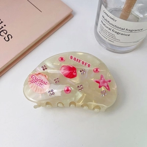 Detailed close-up of cream acetate shell claw clip with pink starfish and rhinestones