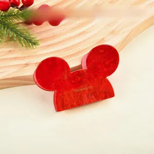 Close-up of red Mickey-shaped acetate hair claw clip with golden brand logo on a festive background