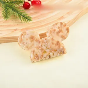 Detail of Mickey-shaped acetate hair claw clip with amber pattern on festive background