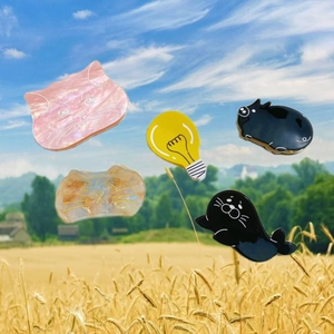 Detailed view of colorful acetate hair claws featuring cartoon cat and bulb shapes