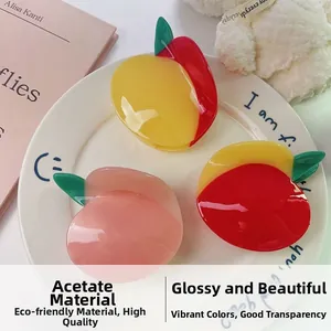 Dettaglio di mollette per capelli in acetato a forma di frutta con design pesca e mango