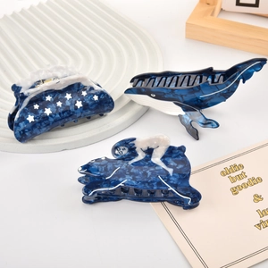 Détail de pinces à cheveux en acétate bleu avec formes artistiques de baleine