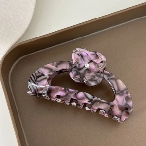 Vue détaillée d'une pince à cheveux en acétate violet marbré avec une fleur de trèfle strass