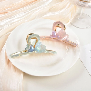 Detail of aurora finish heart hair claws with golden metal springs on silk