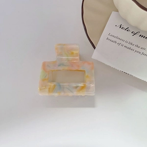 Detail of a large square hollow hair claw clip with colorful marble acetate texture