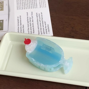 Close-up of cream soda hair claw clip with cherry detail on a vintage tray