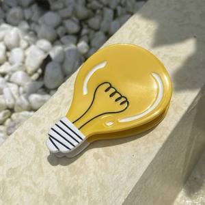 Creative yellow light bulb acetate hair claw clip for women on a stone outdoor background