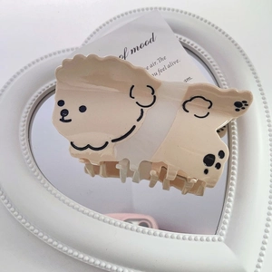 Détail d'une pince à cheveux en forme de chien en acétate sur un miroir en forme de cœur