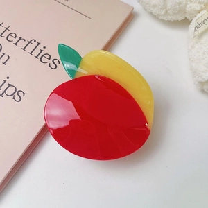 Dettaglio del fermaglio per capelli a forma di mango in rosso, giallo e verde vibrante