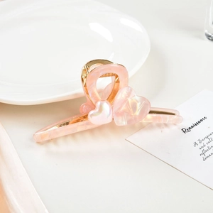 Detailed view of pink marble heart claw clip with golden metal teeth and spring
