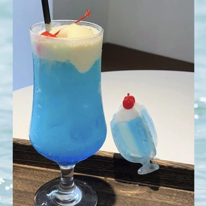 Close-up of a blue cream soda hair claw clip with cherry detail and a summer drink