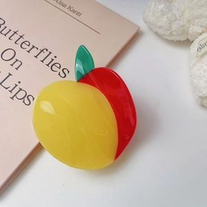 Dettaglio della molletta per capelli in acetato a forma di pesca su un libro rosa